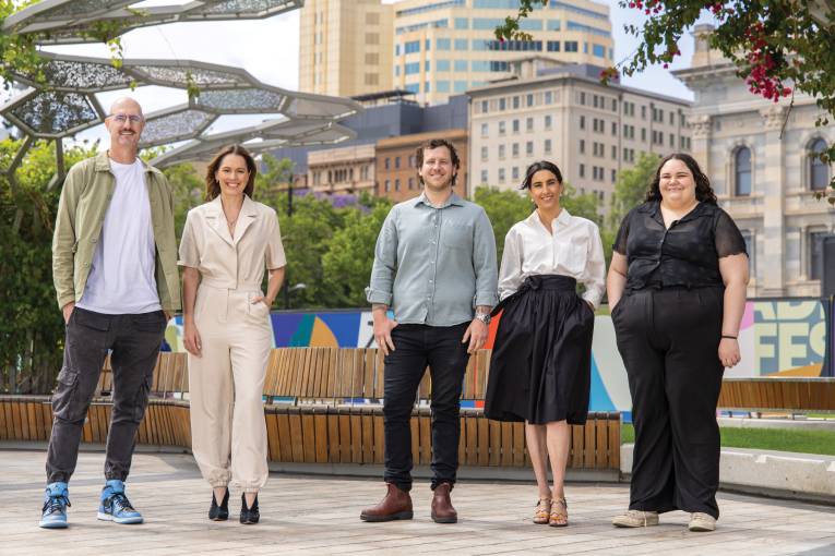 Photograph of five people standing in a plaza