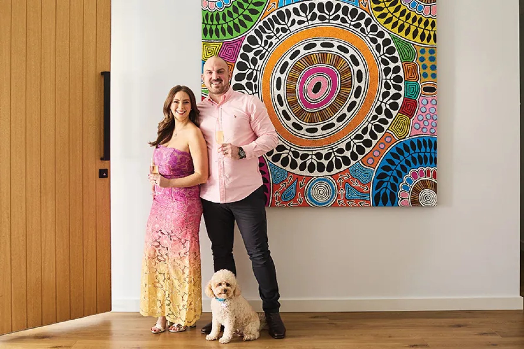 Stacey Lee with husband Ben Millar in front of a colourful piece by First Nations artist Debra Nangala McDonald) has opted for bright styling in both her life and at her Mediterranean-themed dinner party.