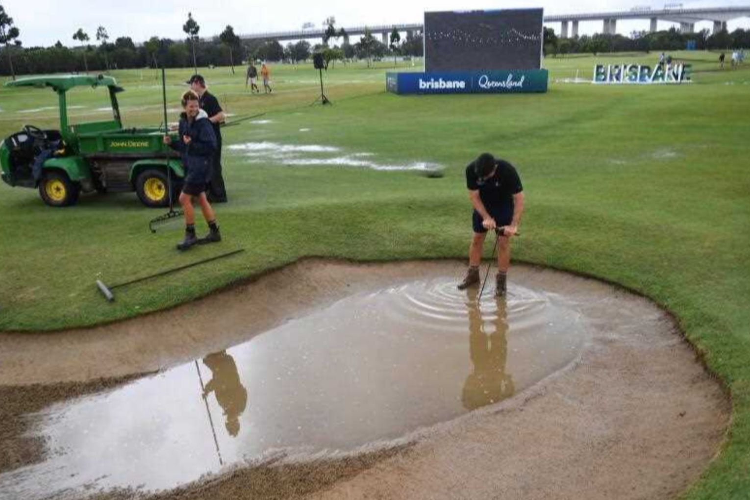 Ground staff attempt to drain a bunker with the rain-hit course now struggling to cope. Photo: Jono Searle/AAP