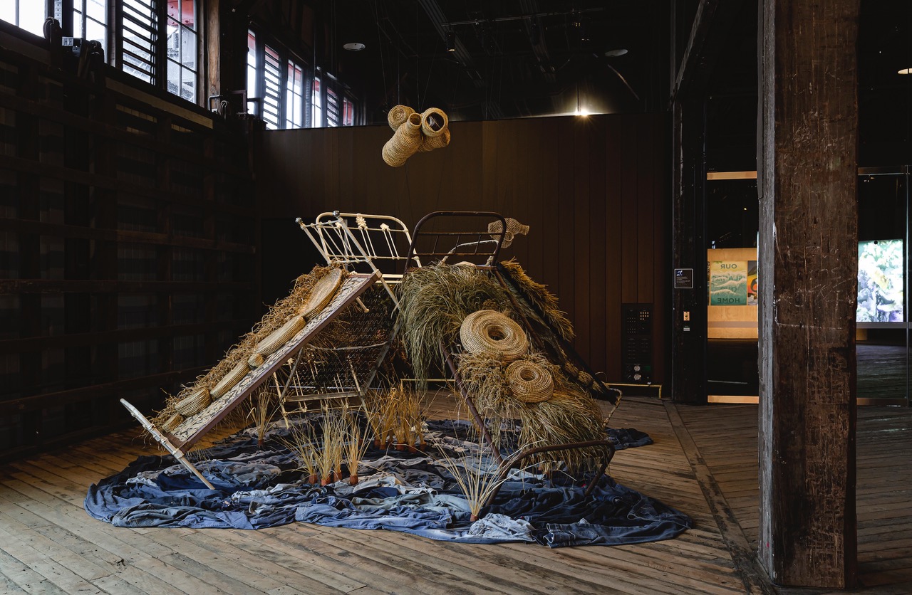 Casino Wake Up Time Slumber Party, 2022-24, antique beds; Australian native plants (buchie rush, bullrush, bracken fern, lomandra, eucalyptus, grass), weeds (umbrella sedge, setaria), terracotta clay, jute string, paper wire twist ties, secondhand denim. Photo: Courtesy of Biennale of Sydney