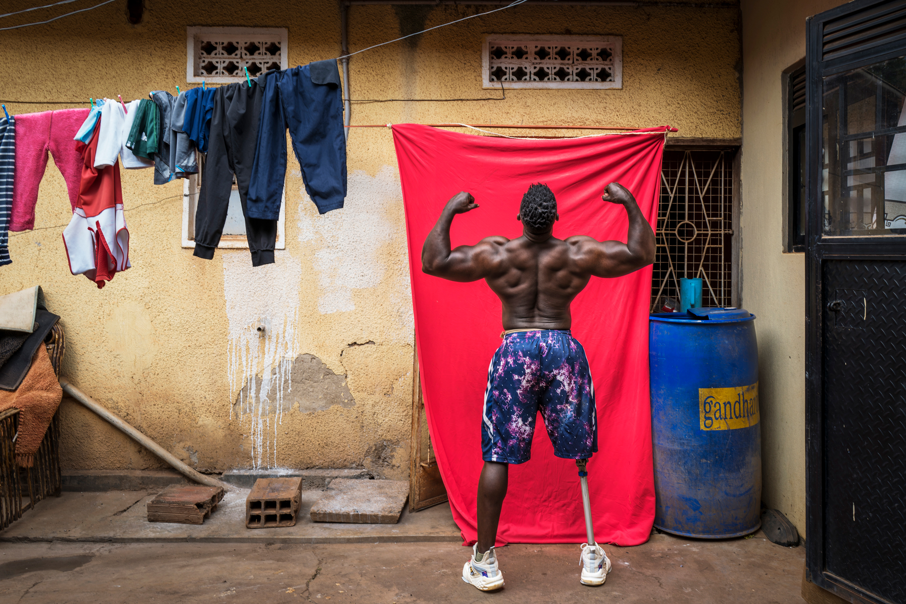 Bodybuilder Tamale Safalu trains in front of his home. Kampala, Uganda, 25 January 2024. © Marijn Fidder