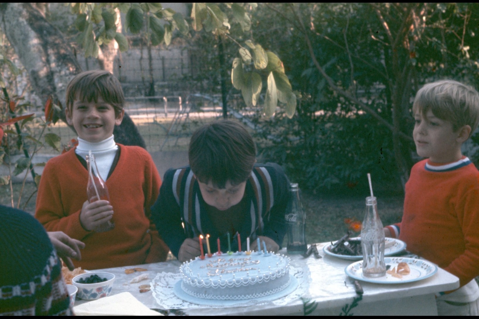 Michael Hutchence beams at the camera while Phil Brown's brother Steve attends to his birthday cake and Rhett Hutchence looks on - in the '60 in Hong Kong.