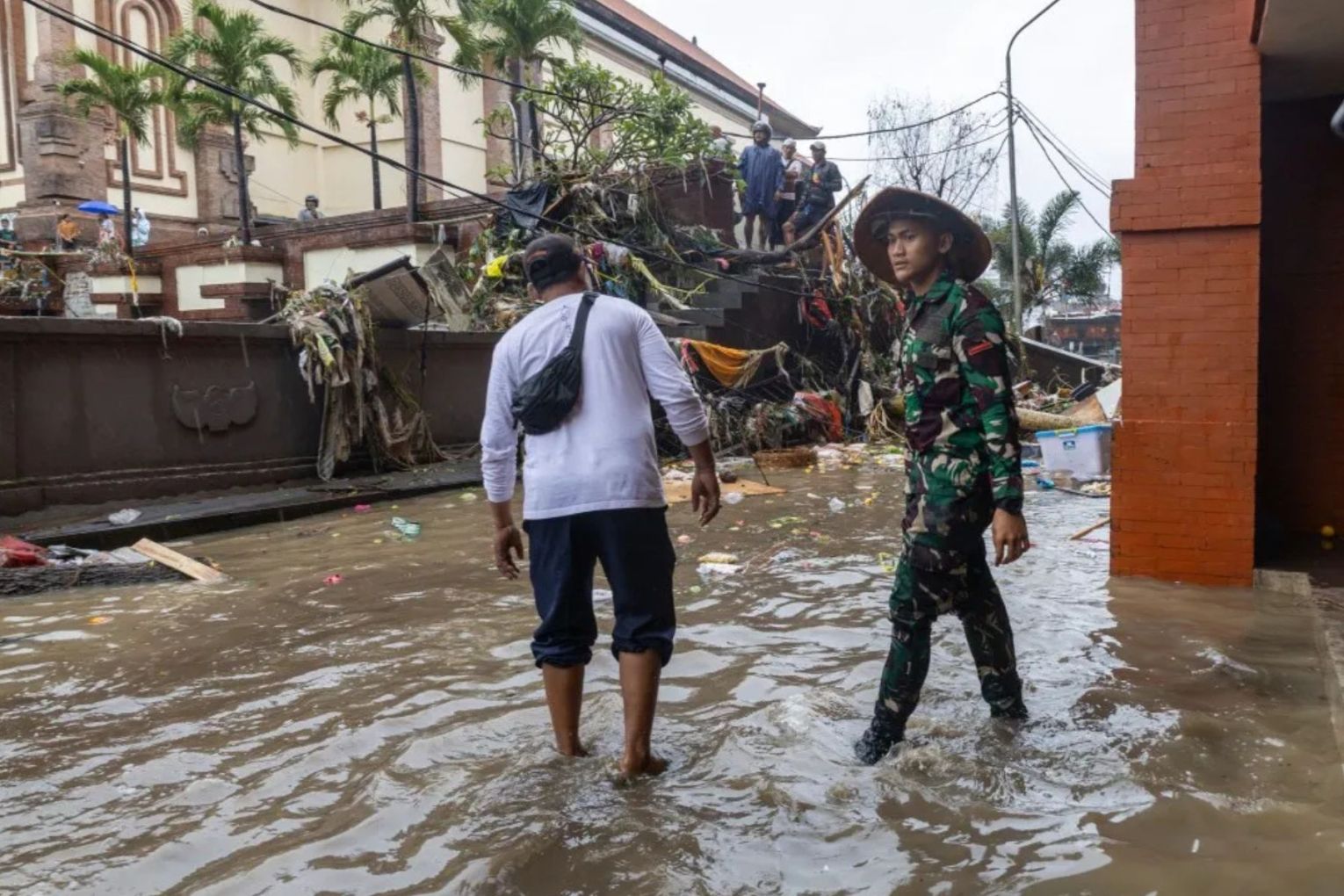 People wade through floodwater at a traditional market in Denpasar, Bali.
