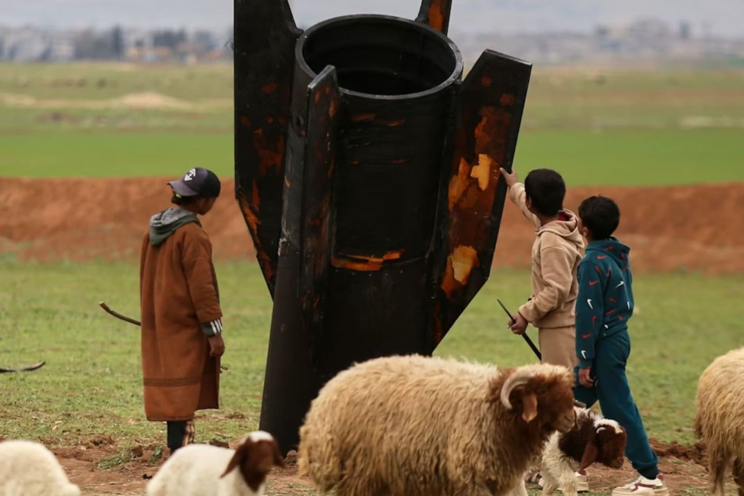 Children inspect an unexploded Iranian missile that landed in an open field on the outskirts of Qamishli, eastern Syria. Picture: Baderkhan Ahmad/AP