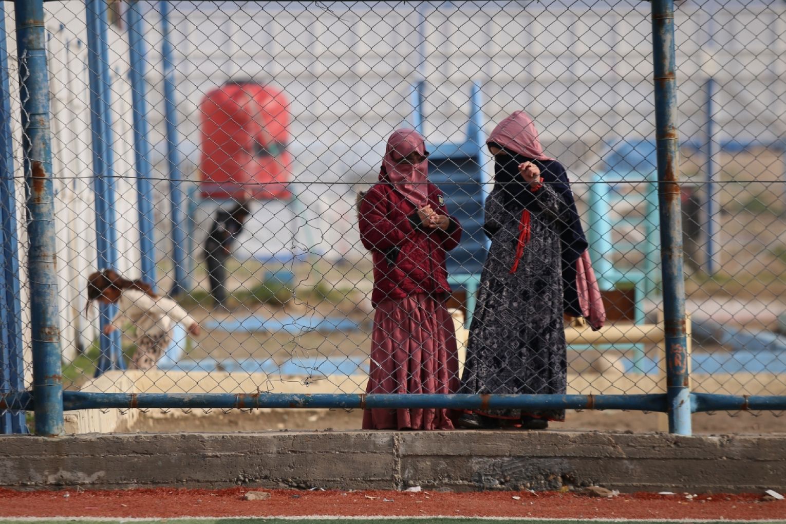 Two women watch boys play soccer on a field at Roj camp, one of the detention facilities holding thousands of Islamic State group members and their families, in the al-Malikiyah area of northeastern Syria, in January this year. Picture: AP Photo/Baderkhan Ahmad