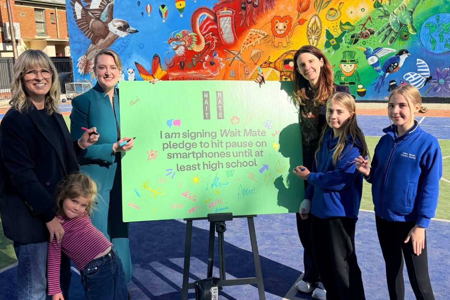 (L-R )Wait Mate SA Director Emily Harrison, Education Minister Lucy Hood, Mother Emma Beech and two of her three triplets, Esther and Betty with the pledge to delay smartphones at Gilles Street Primary School. Picture: supplied. 