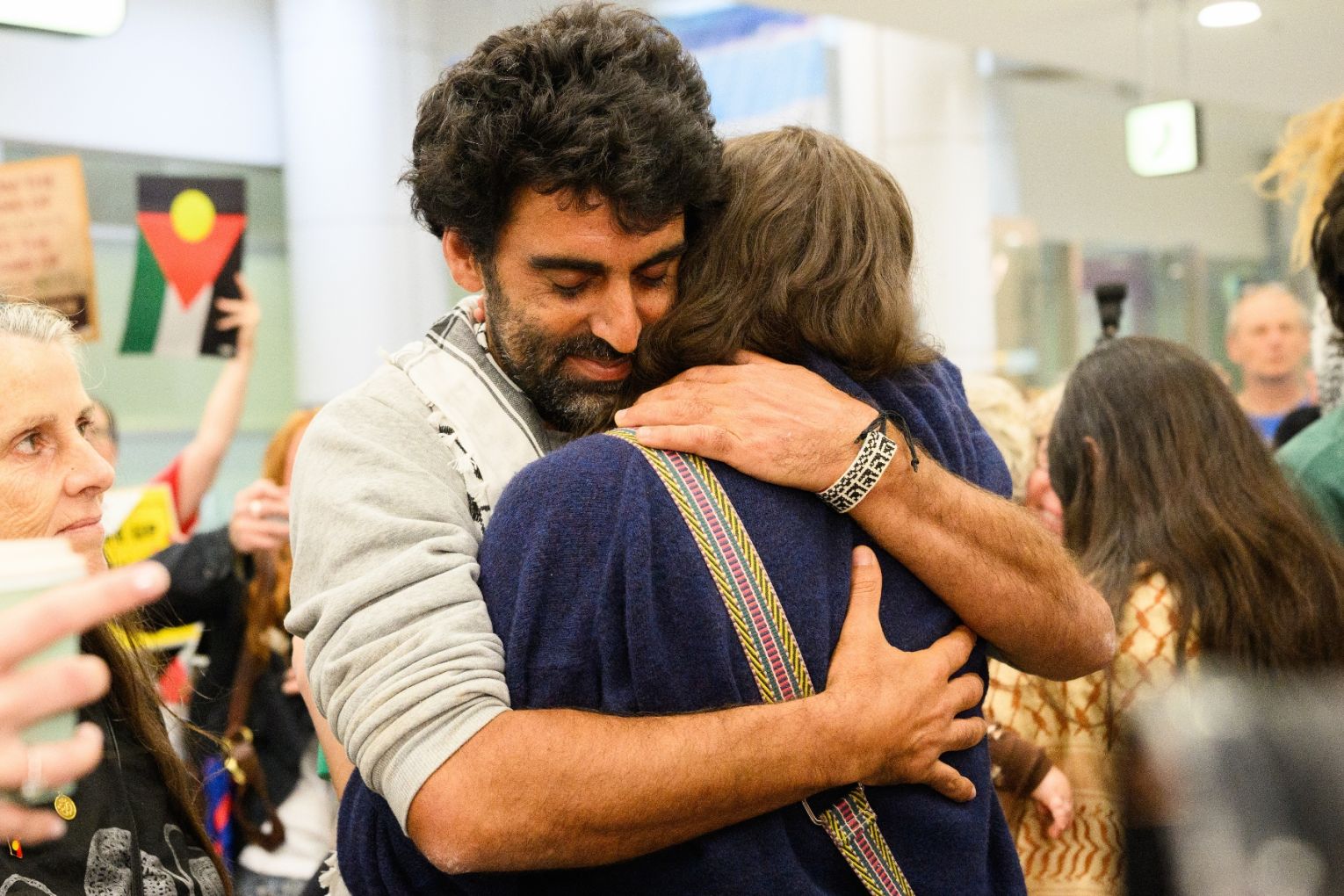Australian activist Surya McEwen is embraced after returning home from being detained by Israel while trying to deliver aid to war-torn Gaza onboard the Global Sumud Flotilla, at Sydney International Airport,Sydney, Monday, May 25. Picture: AAP Image/Bianca De Marchi