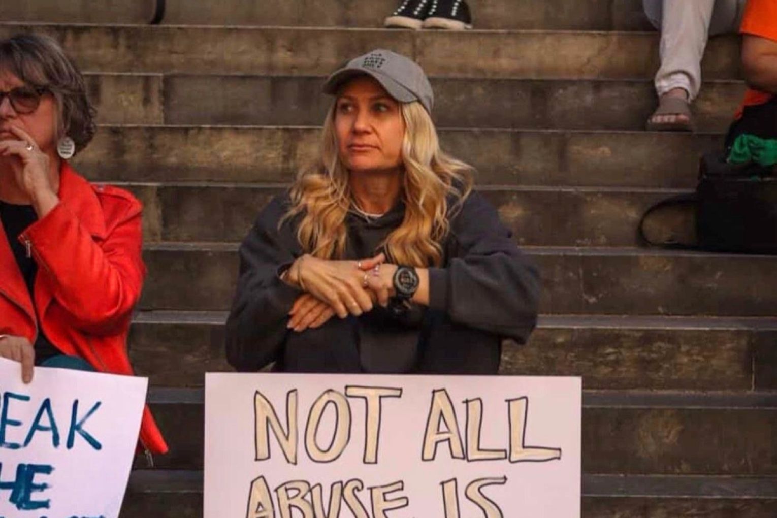 Coercive Control advocate Leesa Scanlan at the steps of Parliament House with a sign that reads "not all abuse is loud, but we must be". Picture: via LinkedIn