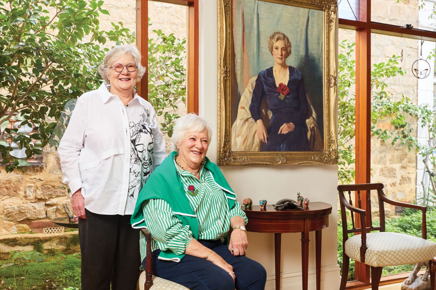 Joan and Didy next to a portrait of their grandmother Lady Holden.